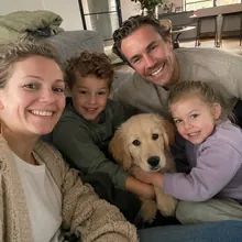Sanne en Mark op de bank met hun twee kinderen, hun dochter houdt golden retriever-pup Bowie vast